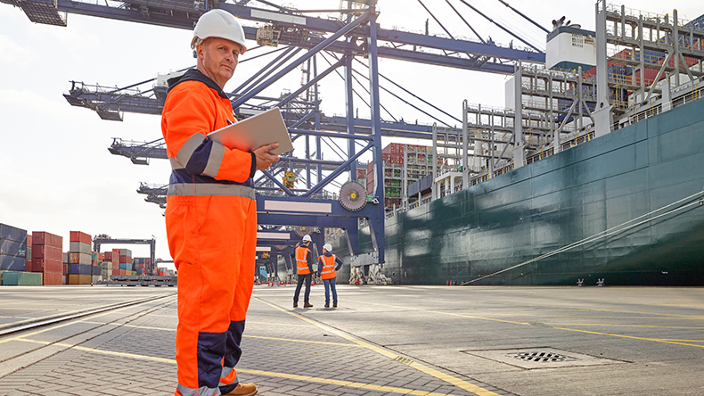 Dock worker with digital tablet beside cargo ship at Port of Felixstowe Credit: Luxy Images Limited / Alamy Stock Photo