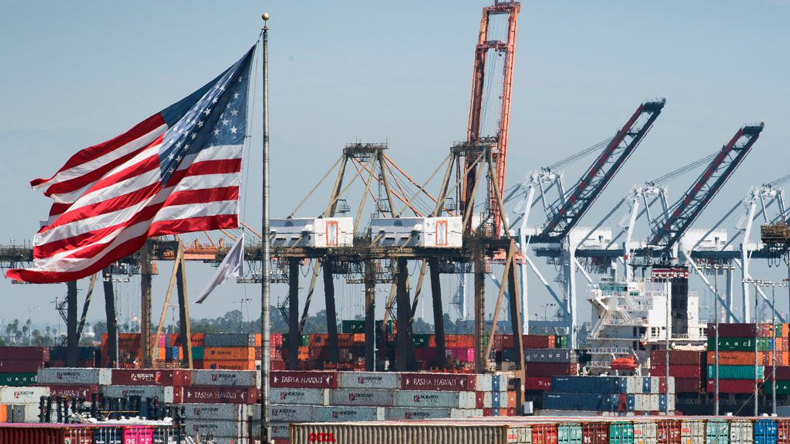 US flag flying in front of containers and cranes at Los Angeles port: credit Mark Ralston/AFP via Getty Images