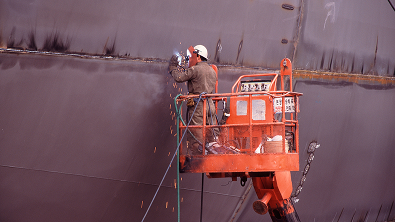 shipyard worker welding hull section of new containership in dry dock pusan south korea Kevpix / Alamy Stock Photo