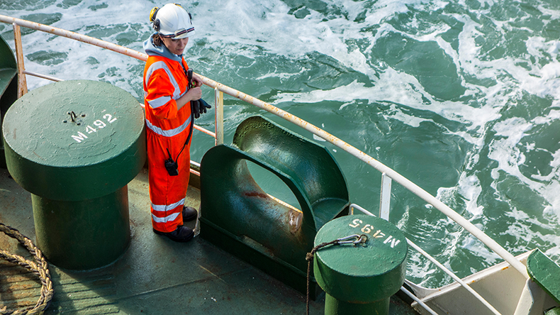 Female crew member in orange overall at sea