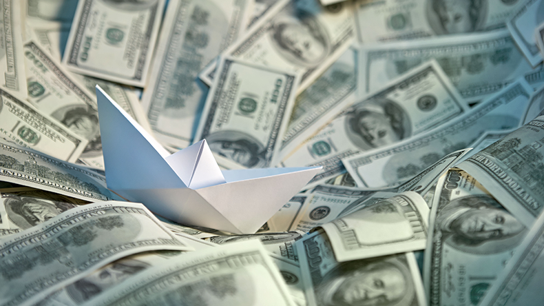 Paper ship on sea of money