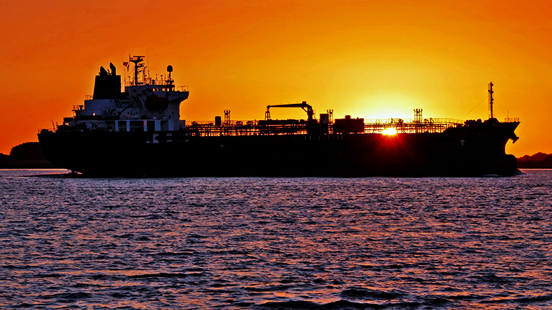 Product tanker at sea backlit with rising sun